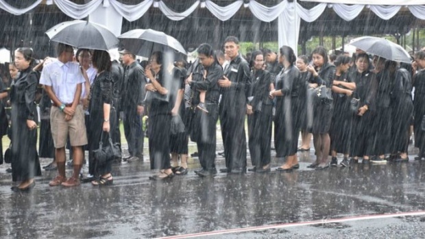 ฝนหนักก็ไม่ท้อ ประชาชนยืนต่อแถวอุ้มลูกน้อยกลางสายฝน รอวางดอกไม้จันทน์เมืองคอน