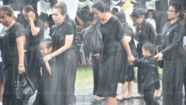 ฝนหนักก็ไม่ท้อ ประชาชนยืนต่อแถวอุ้มลูกน้อยกลางสายฝน รอวางดอกไม้จันทน์เมืองคอน