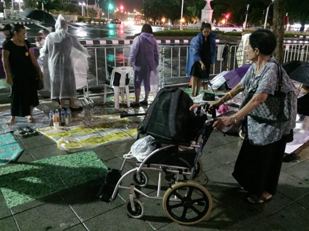 ประชาชนนอนฝ่าฝนจับจองพื้นที่โดยรอบถนนราชดำเนินใน เฝ้ารองานพระราชพิธี