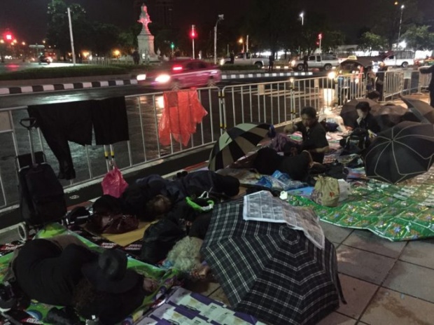 ประชาชนนอนฝ่าฝนจับจองพื้นที่โดยรอบถนนราชดำเนินใน เฝ้ารองานพระราชพิธี