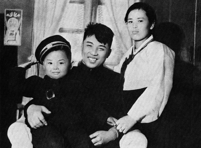 คิมจองอิลวัยเด็ก อยู่ในอ้อมกอดของ คิมอิลซุง บิดาและผู้นำเกาหลีเหนือยุคแรกใต้ร่มธงคอมมิวนิสต์