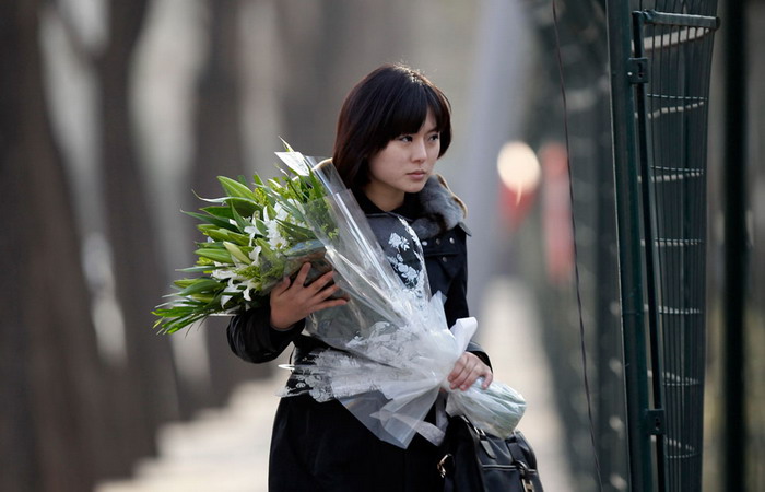 สตรีเกาหลีเหนือนำดอกไม้ไปวางไว้อาลัย คิมจองอิล ที่หน้าสถานทูตเกาหลีเหนือในกรุงปักกิ่ง ประเทศจีน